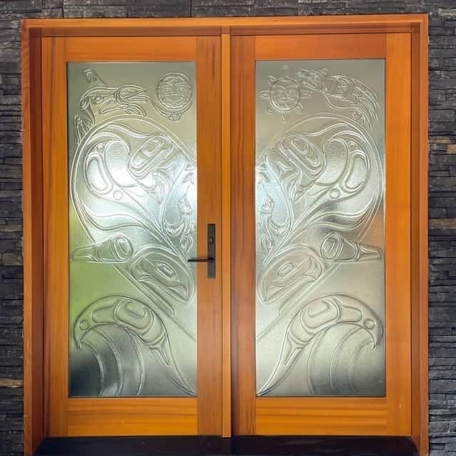 Full-height double entry doors with carved-glass eagle, salmon and sun panels