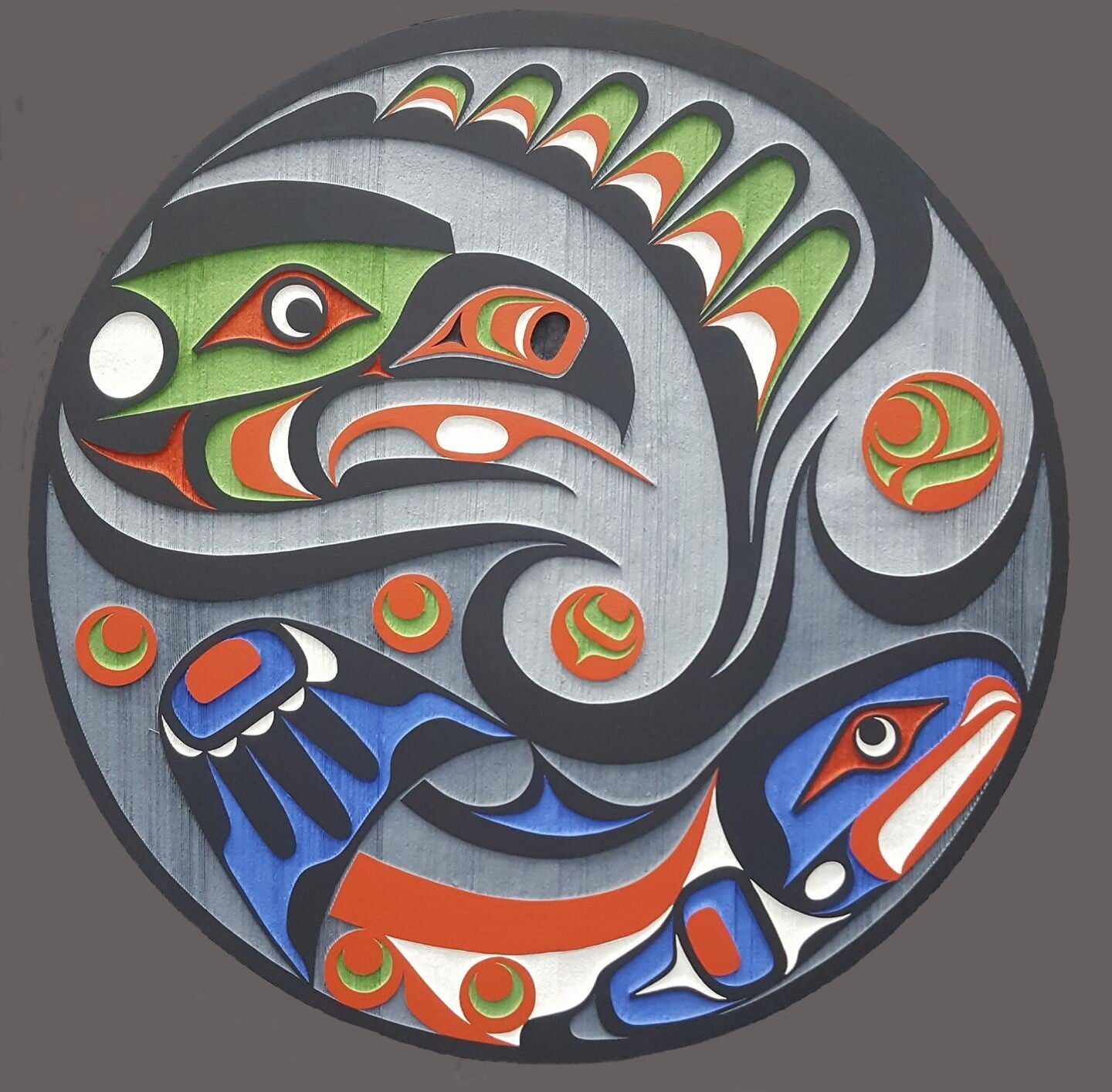 Silver-grey round panel with a green and red eagle diving at a blue and red salmon