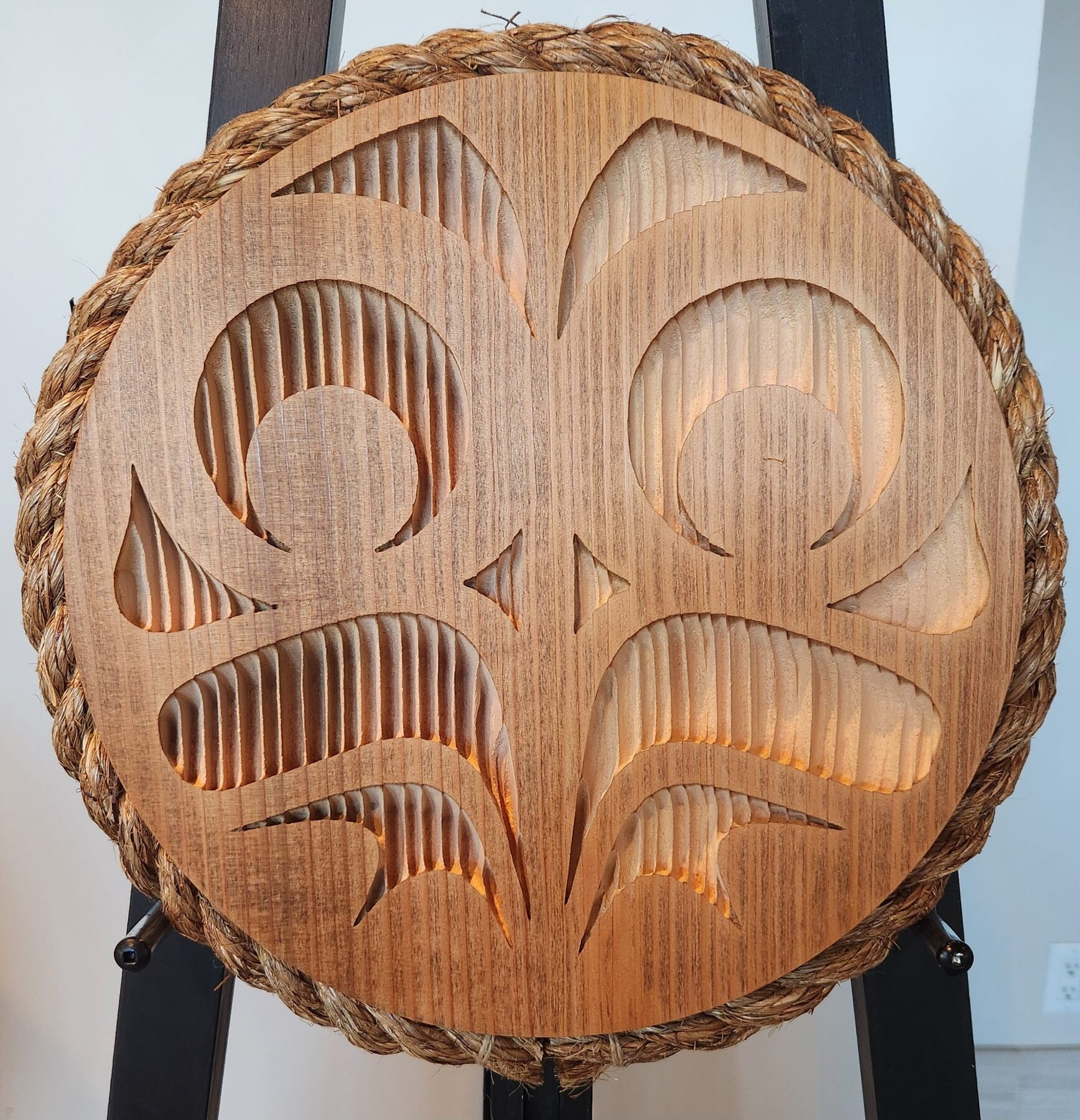 Backlit round owl panel in plain cedar with a rope rim, on a black easel