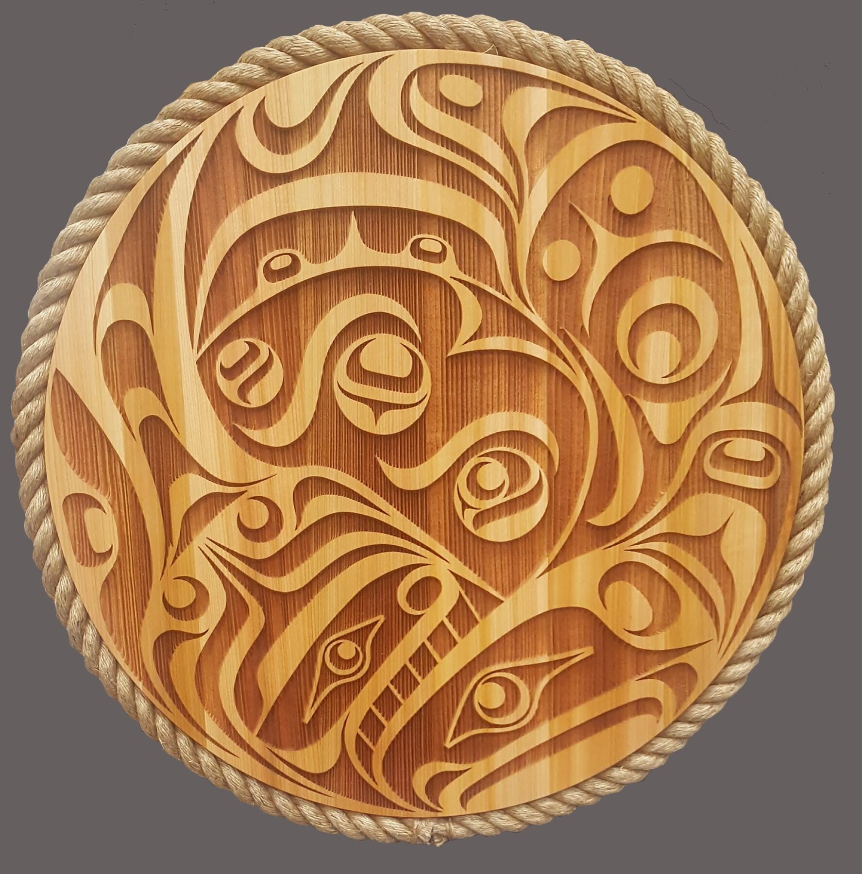 Oiled plain-cedar round panel carved with salmon faces and egg circles