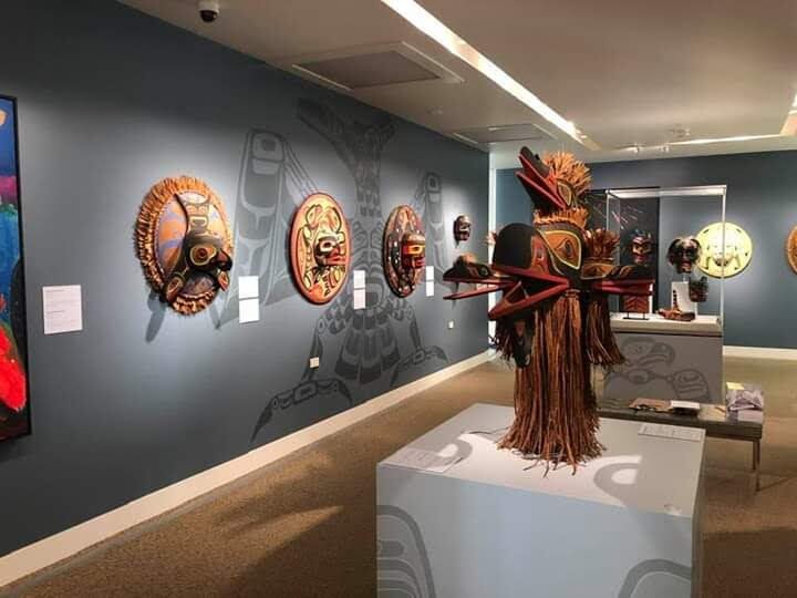 Gallery exhibition room hung with round carved panels and a carved figure on a plinth