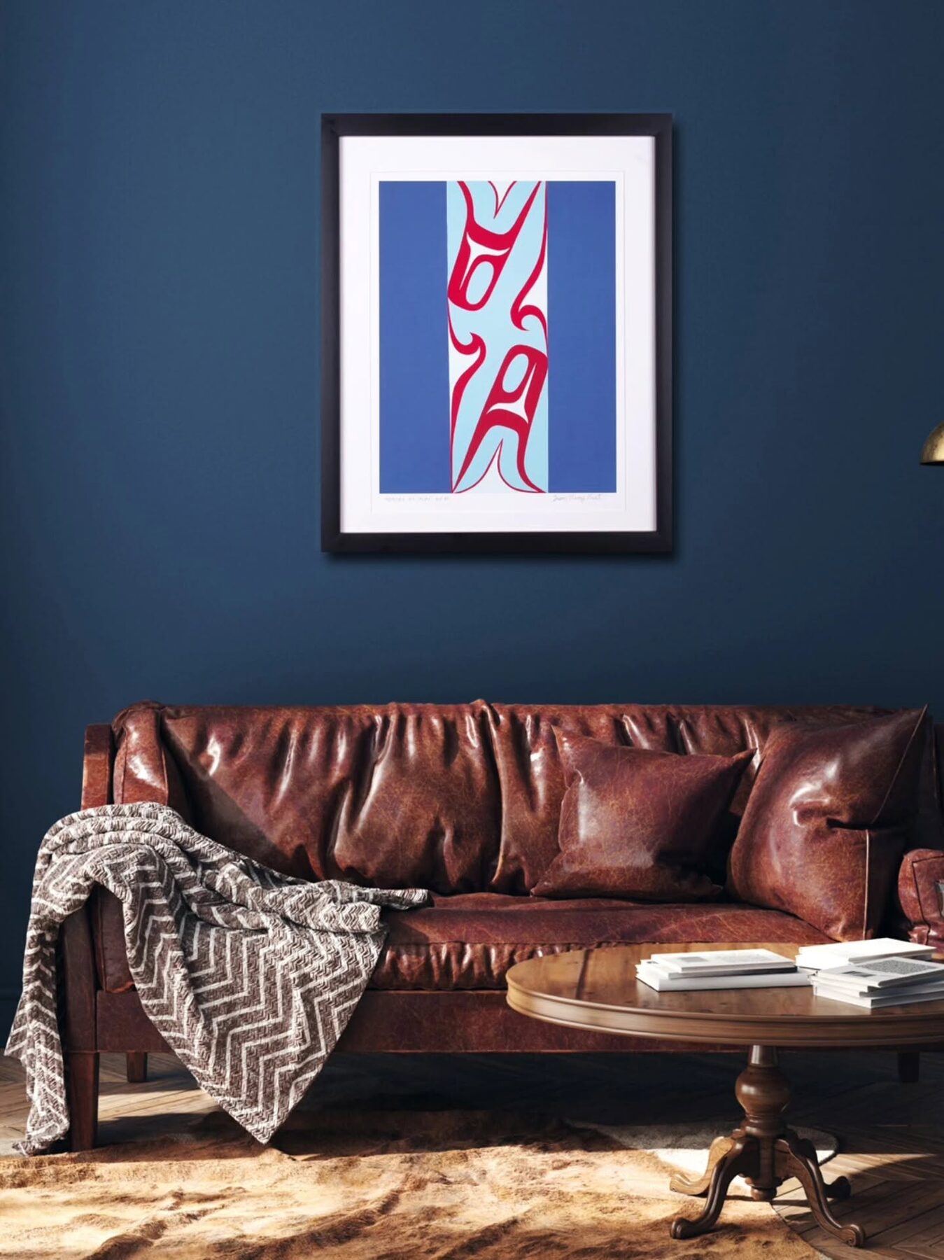 Framed Orcas at Play print in red on pale blue, hanging above a leather sofa