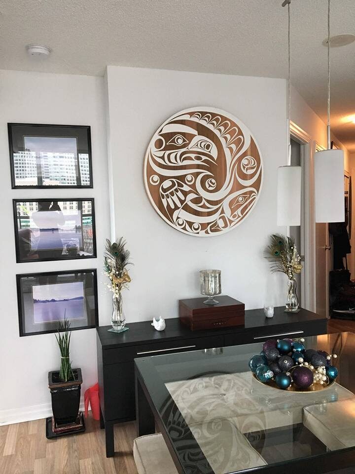 Round cedar panel with a white-painted eagle design hanging in a collector's dining room