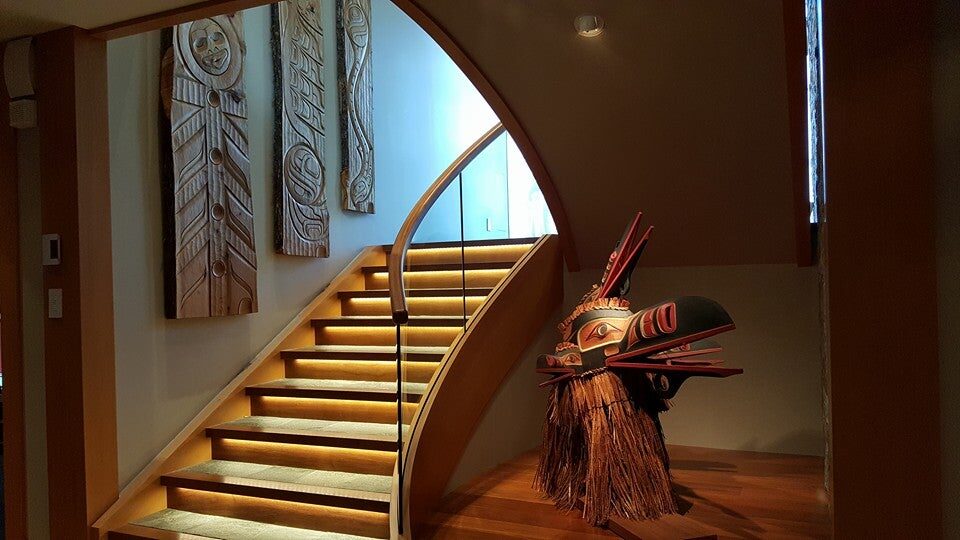 Staircase with carved powerboards and a cedar-fringe raven mask